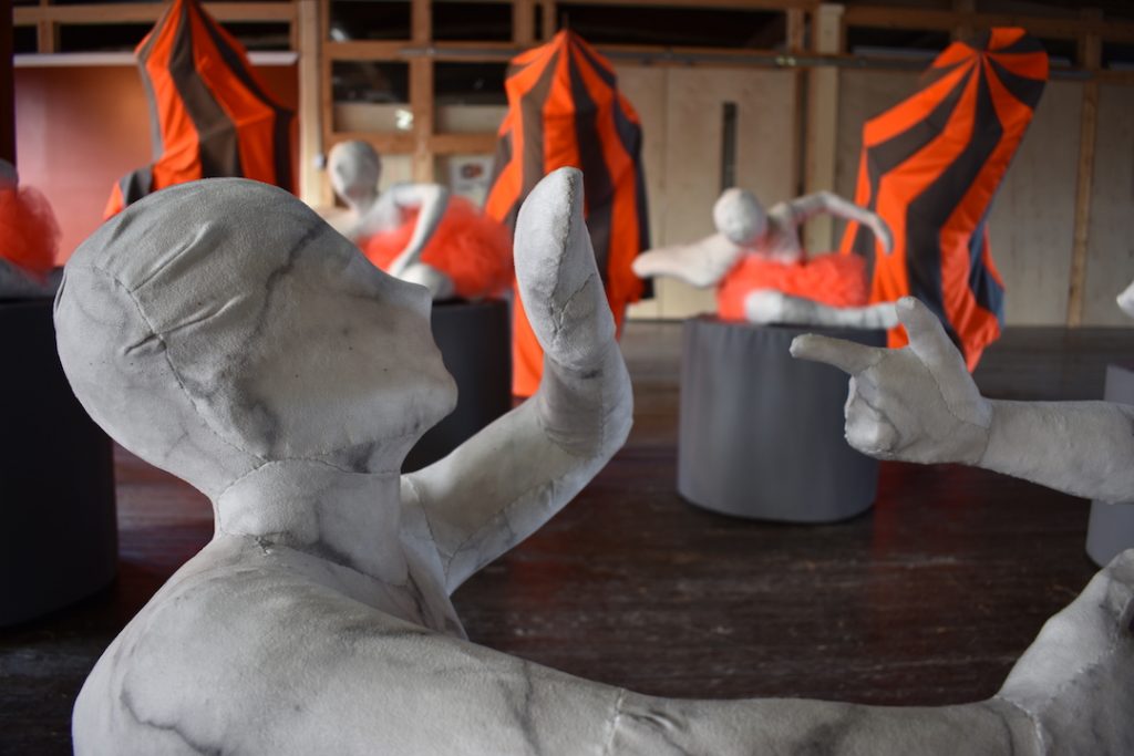Sculpture by Cara Sawka:
Circus of Life
2015-2017
Front Centre: Play Fight
Middle Row: The Cast
Back Row: Heavy Sighs
faux marble printed on faux suede upholstered over plaster, wood, metal, mixed textiles
in the foreground one of two main sculpture figures are seen upholstered in faux marble printed on faux suede, blocking a defensive move coming in from off screen from the thumb and forefinger of another figure in the shape of a pistol. The background displays a couple of similar figures that appear as if they are in motion while sitting on pedestals draped in grey fabric - they have blaze orange tutus on. Behind them are tall slender anthropomorphic tents with alternating blaze orange and grey stripes.
Funding support thanks to Arts Nova Scotia